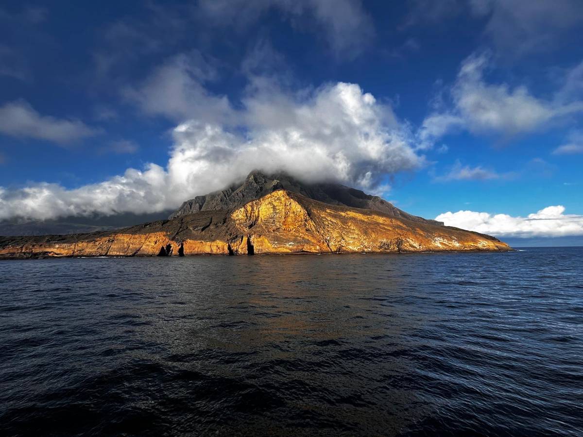 Volcanic island in the Galapagos archipelago in golden light from the deck of the Yate Anahi