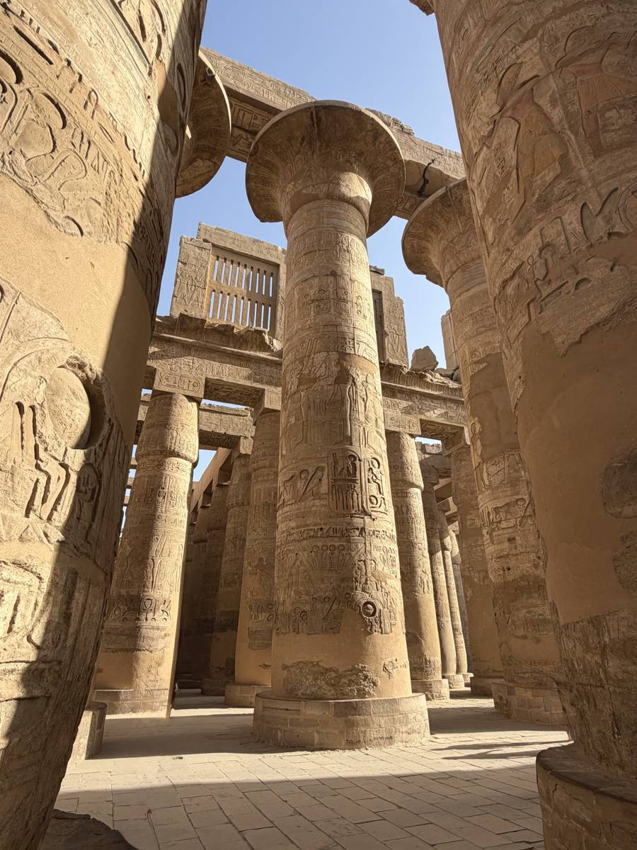 Towering columns covered in hieroglyphics inside the Hypostyle Hall at Karnak Temple in Luxor, Egypt